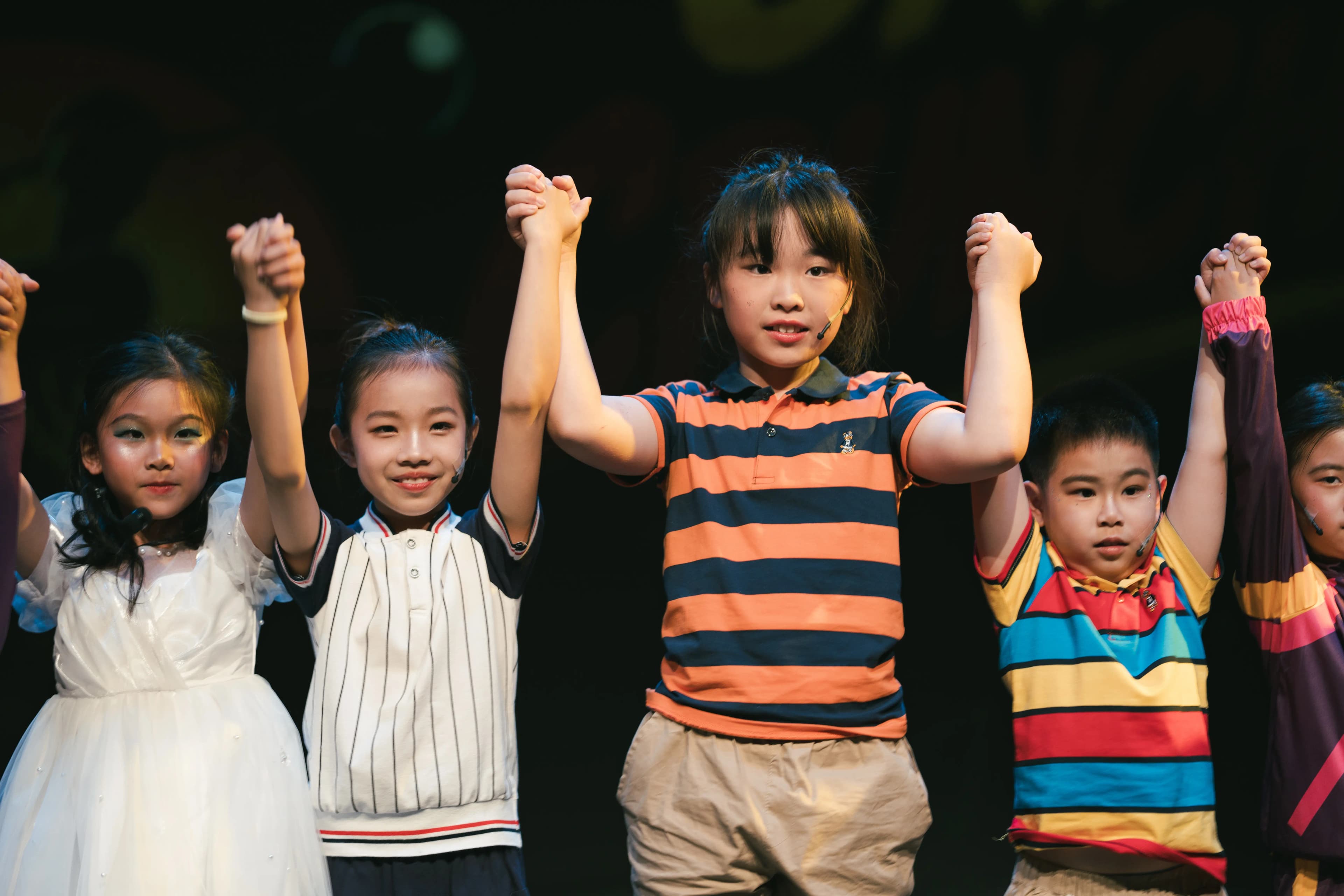 Students holding hands and bowing together after a stage performance.