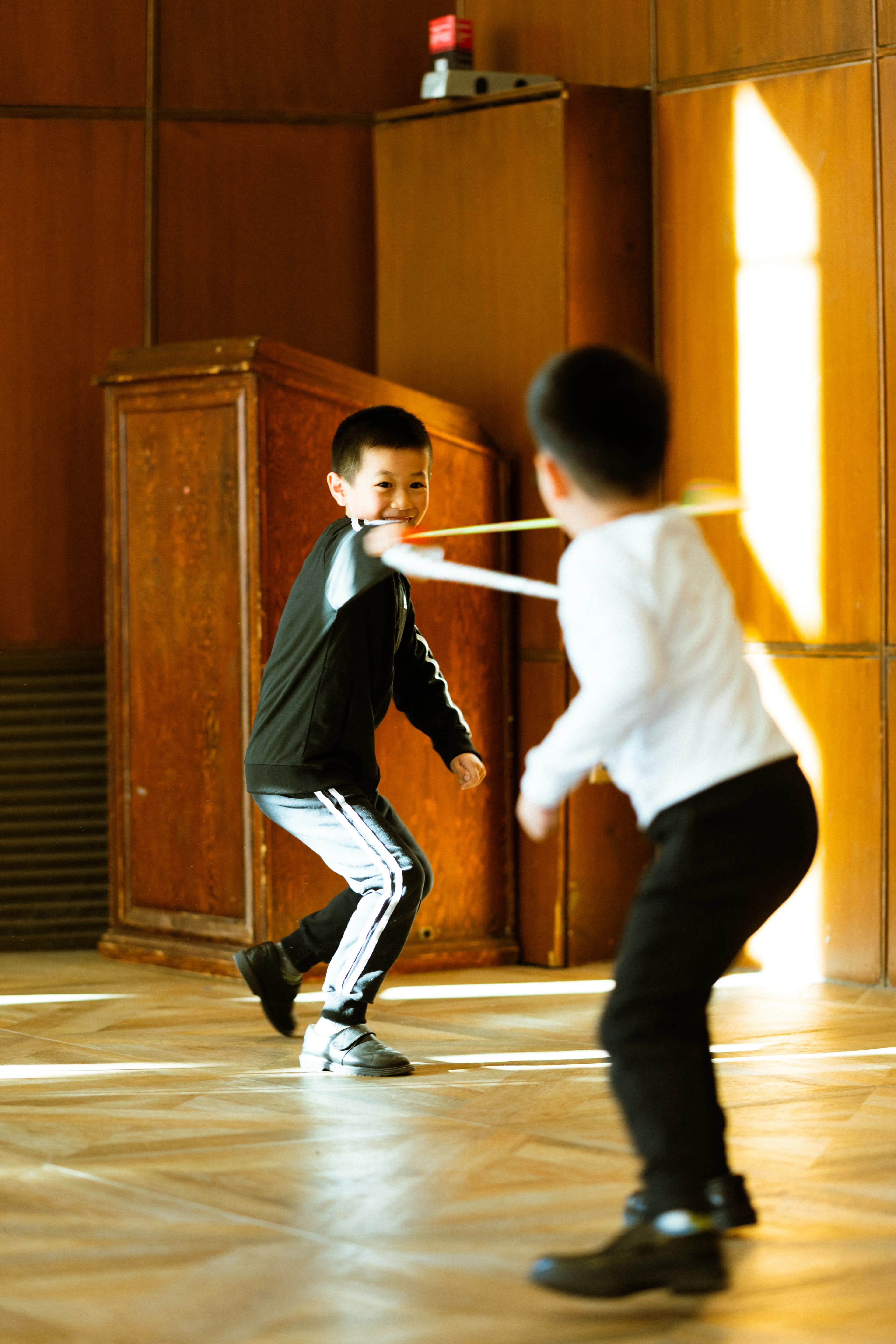 Young TADA performers play fighting with swords, during some down time in class.