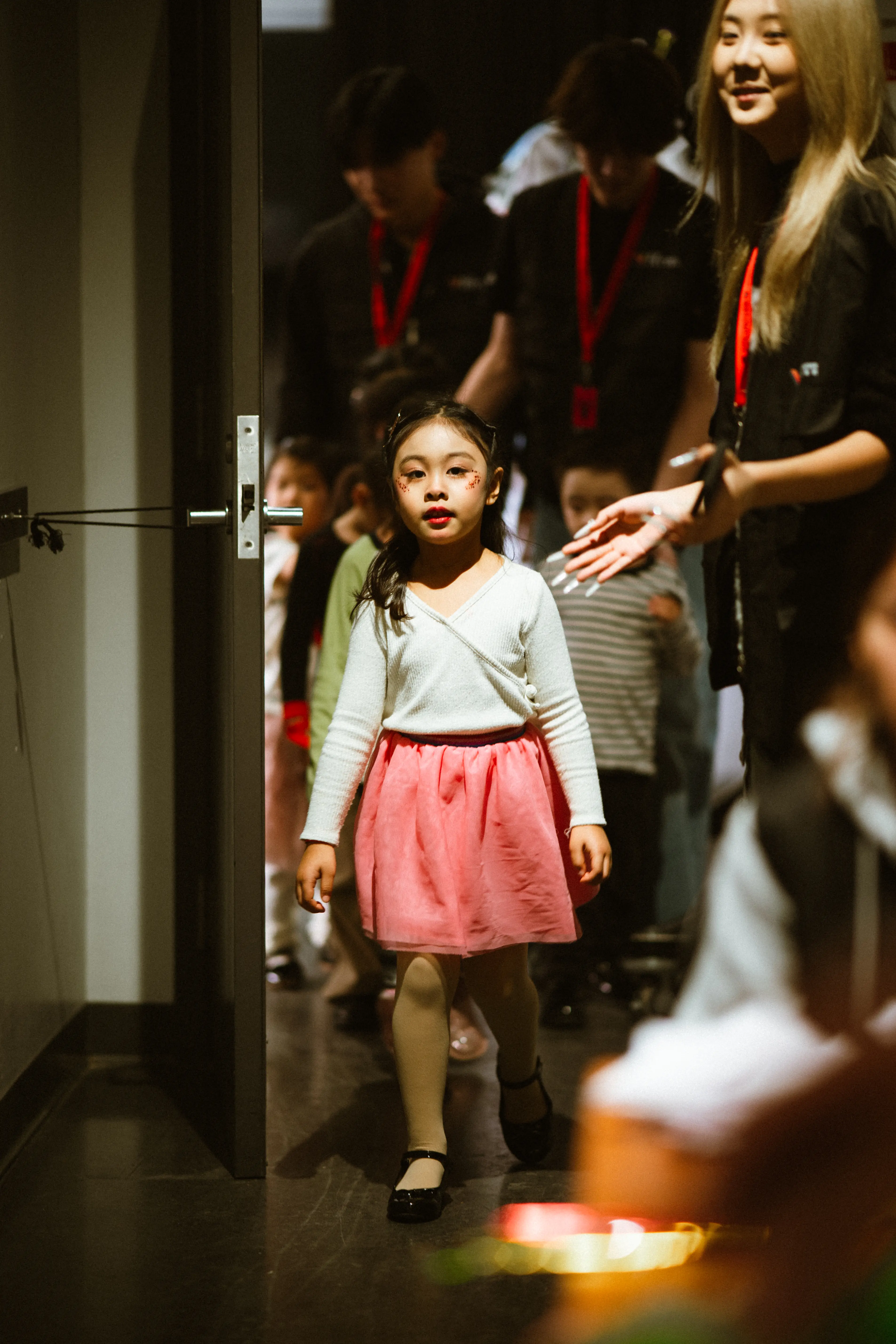 A young TADA student walking backstage with support from an educator.