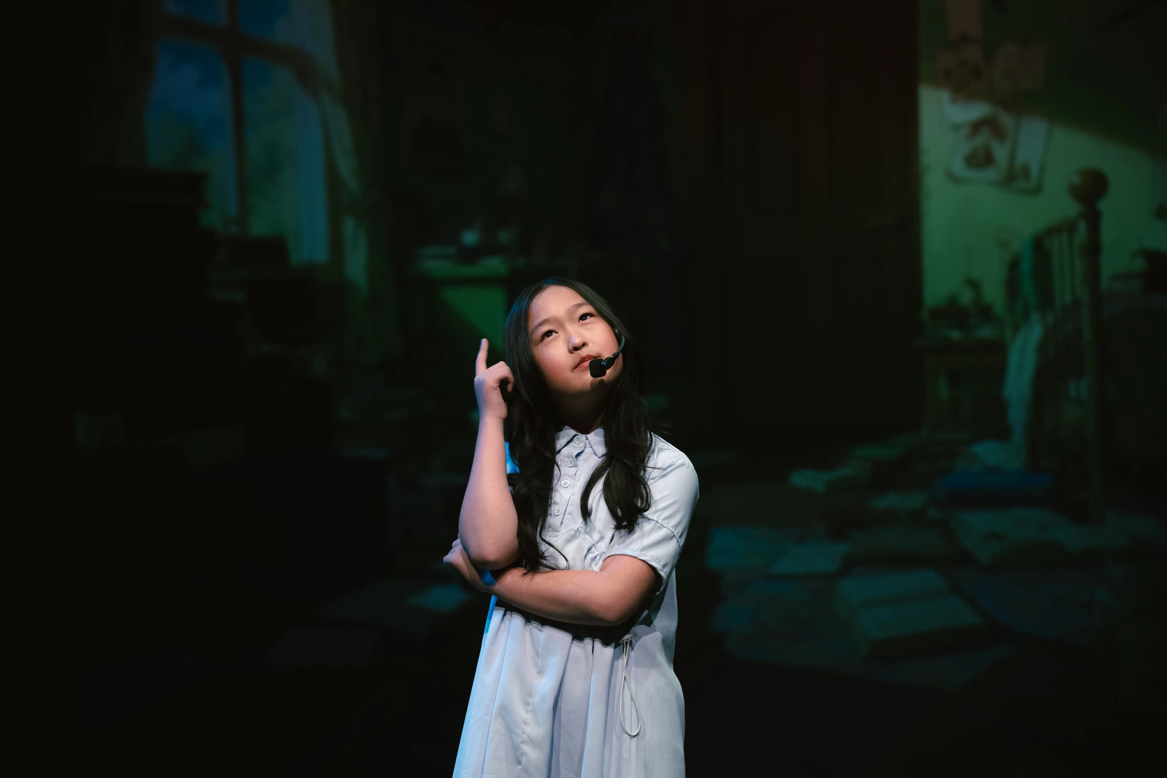 A young performer gestures during a solo scene onstage.