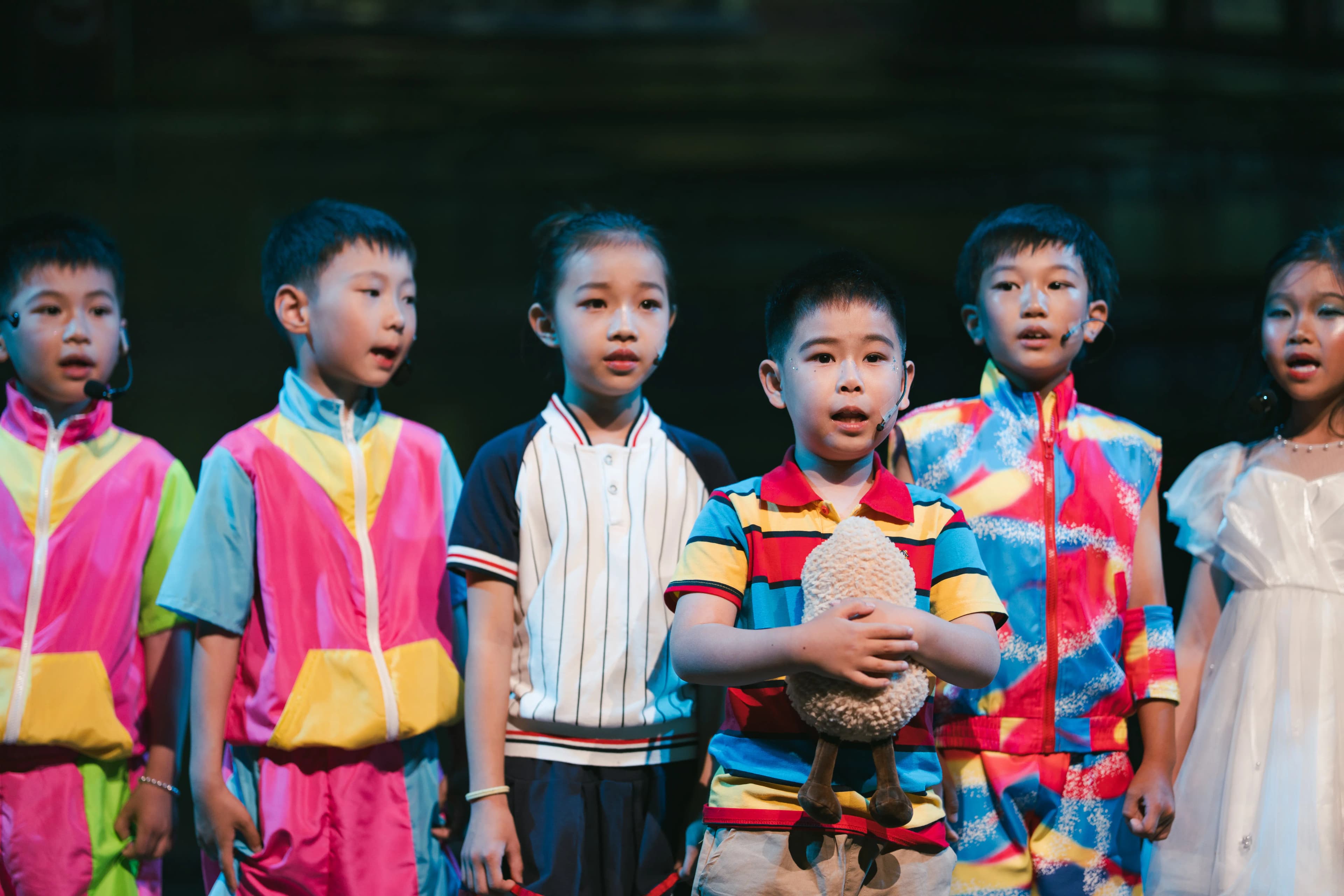 Young TADA performers singing together on stage.