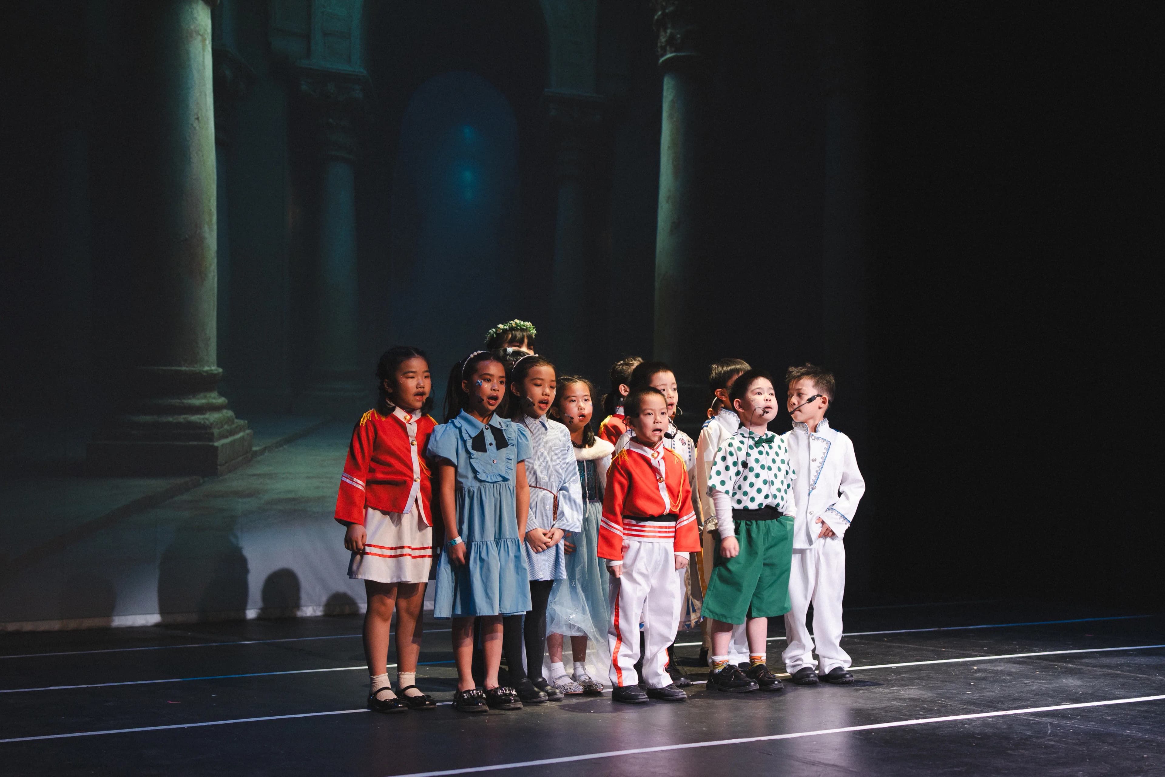 A costumed student ensemble performs together onstage.
