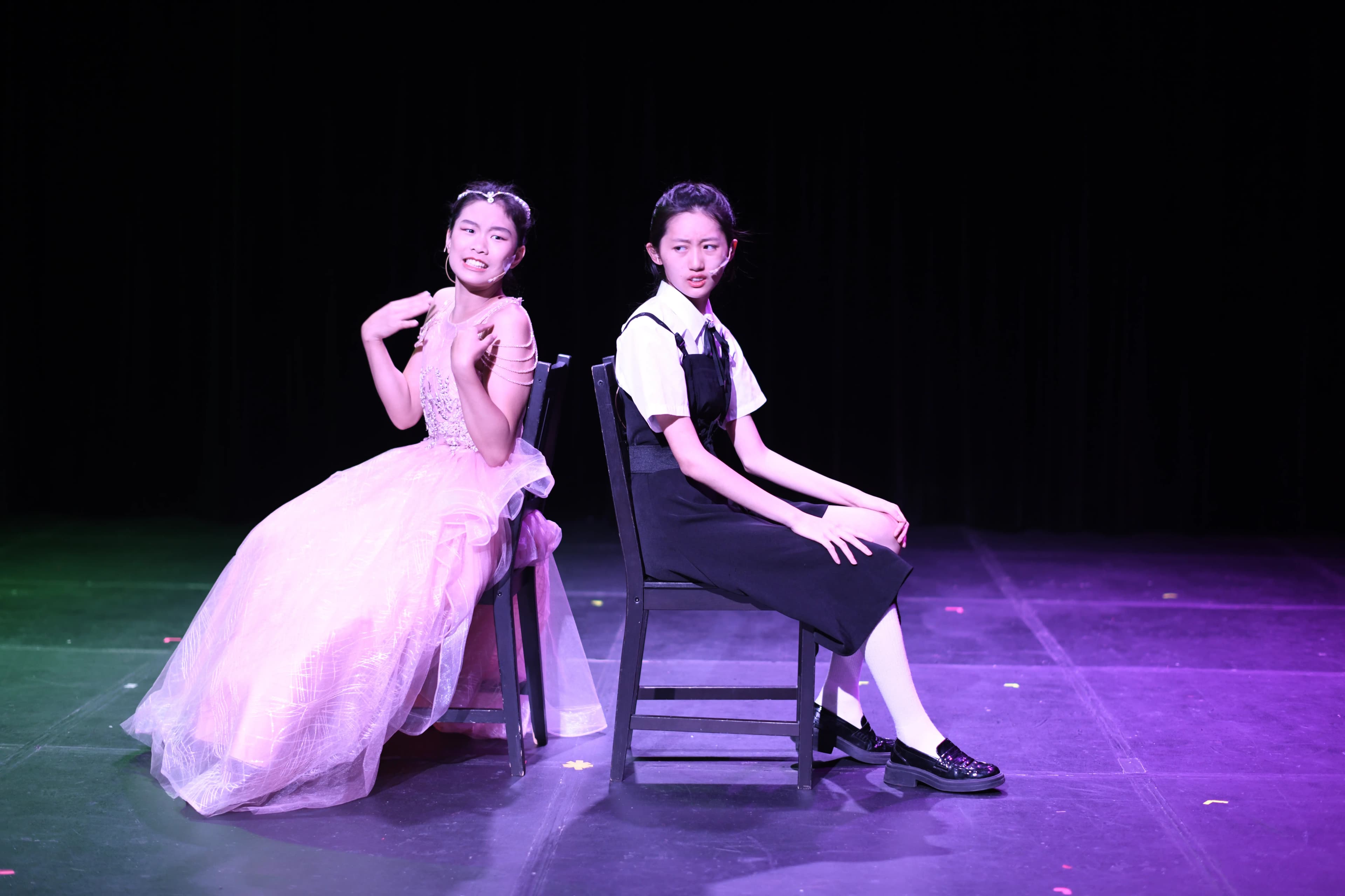 Two students, dressed as opposites are sitting back to back, angry and hateful with each other.