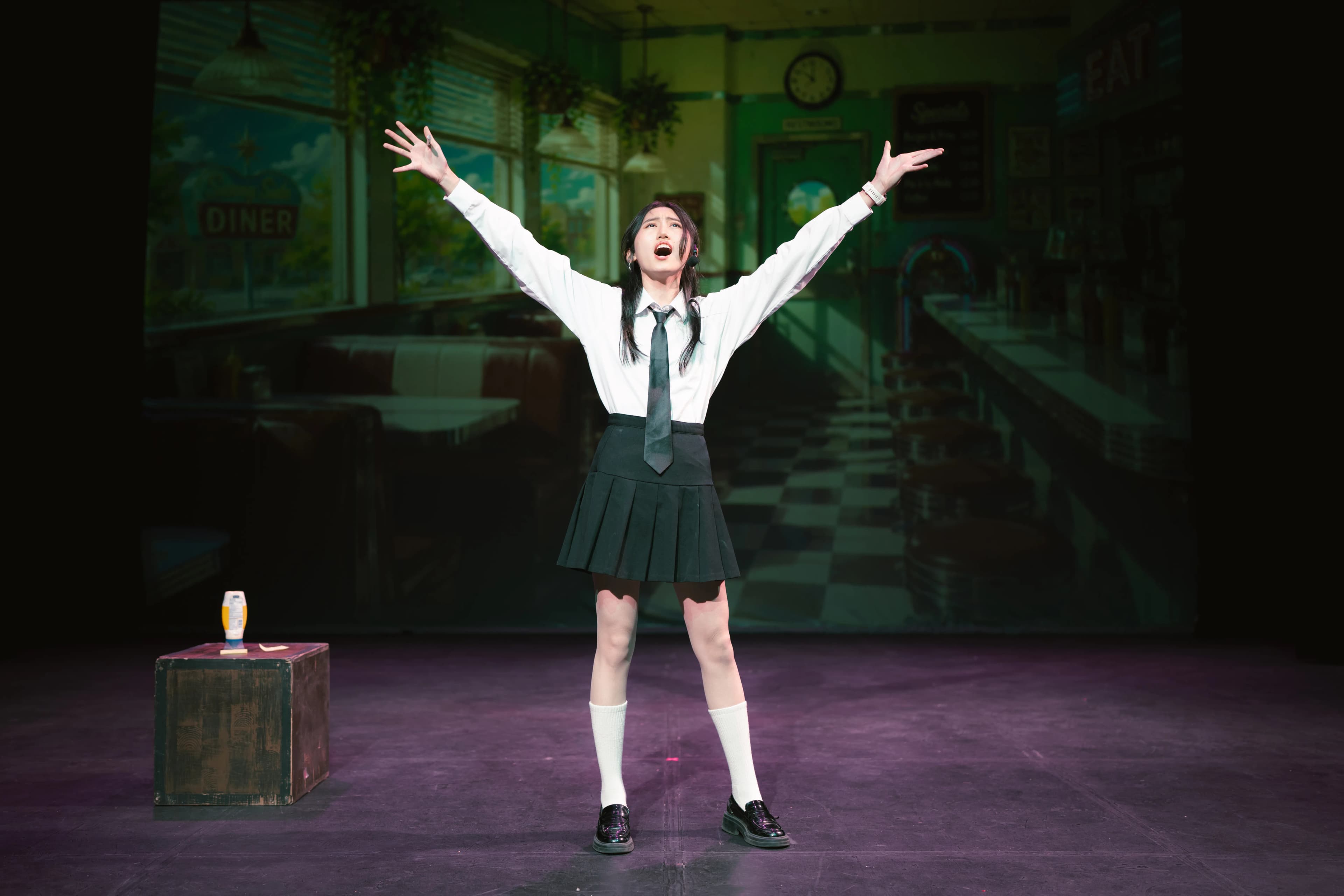 A student singer holds her arms wide during a solo onstage.