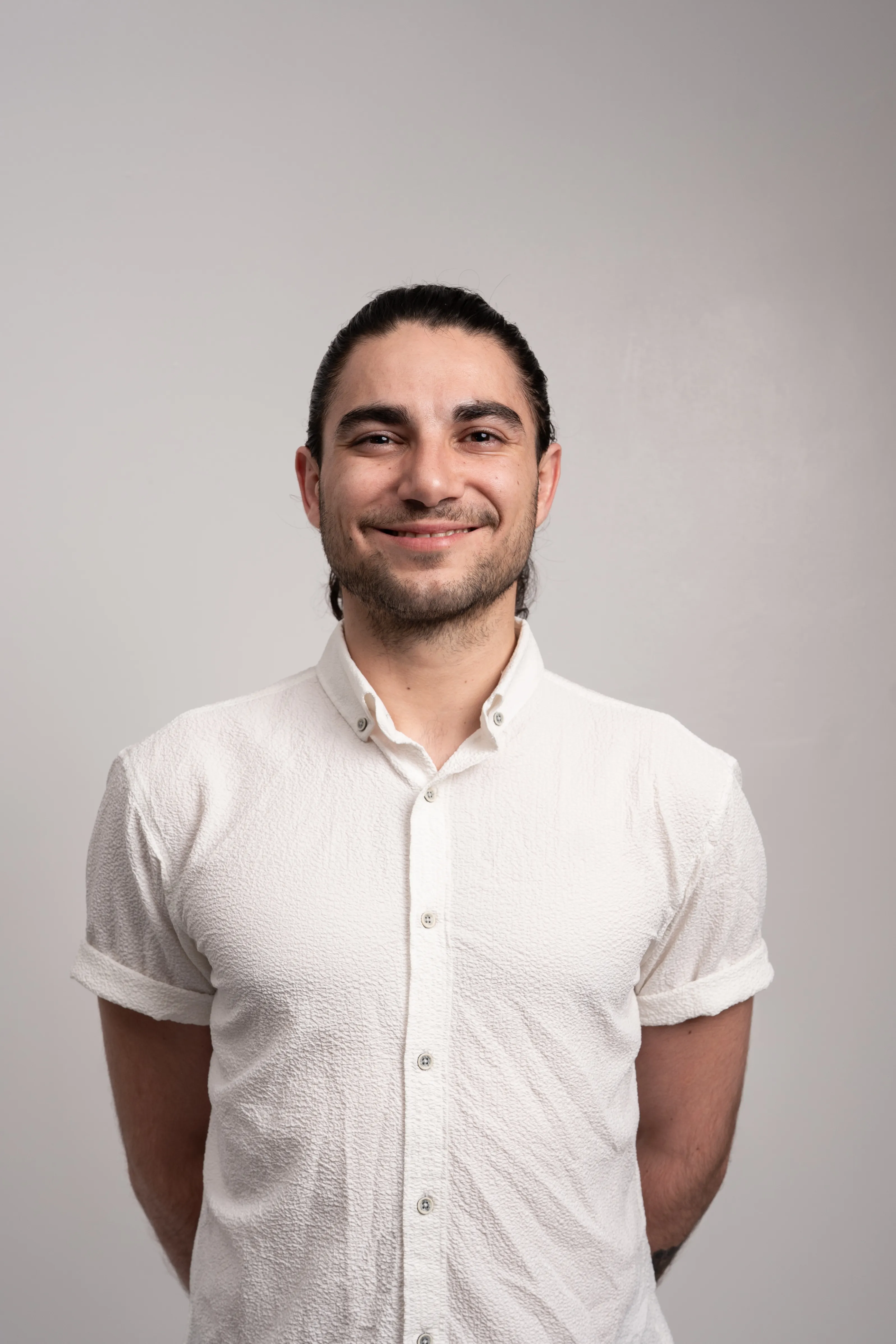 A professional headshot of our teacher, smiling in a textured white button up shirt.